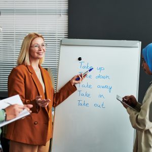 Confident mature teacher of English language pointing at whiteboard